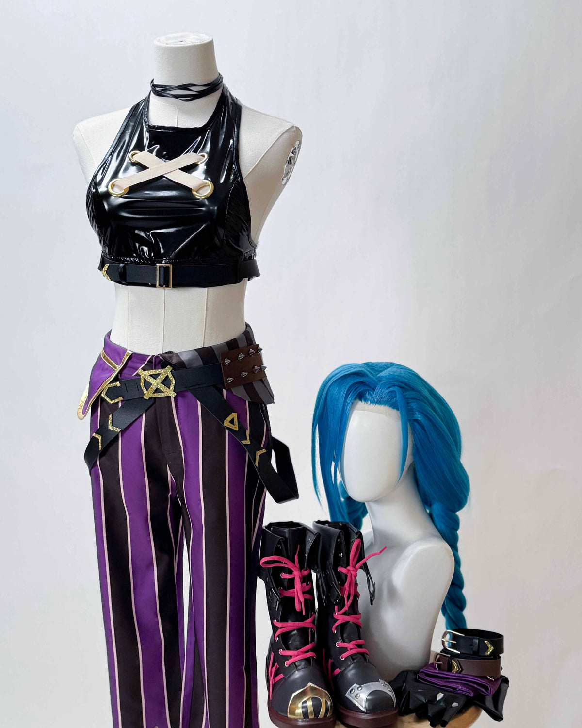 Closer view of the Jinx Arcane cosplay outfit showing crossed chest straps, belt details and a blue braided wig