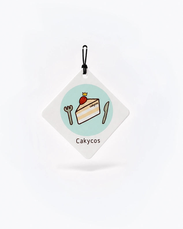 Cakycos scented hanging paper with a cake illustration, white diamond-shaped card and black hanging cord
